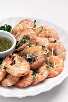 fresh boiled prawns with zesty citrus dipping sauce on white table

