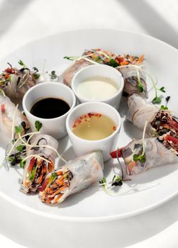 asian fresh vegetable vegan spring rolls with sauces on white restaurant table background in hanoi vietnam