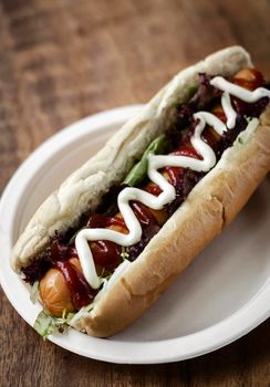 classic hot dog with frankfurter sausage and sauces on wood table