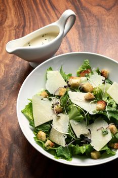 caesar salad with parmesan cheese and croutons on wood table