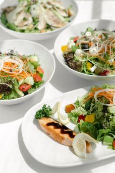 mixed fresh organic salads in bowls on white restaurant table