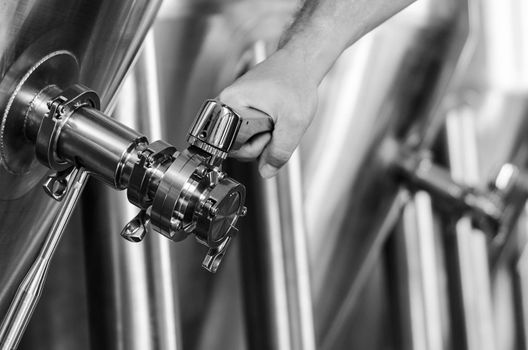 brewer operating industrial beer brewing equipment in brewery interior in black and white