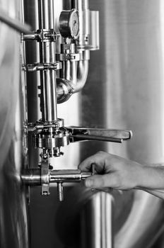 brewer operating industrial beer brewing equipment in brewery interior in black and white