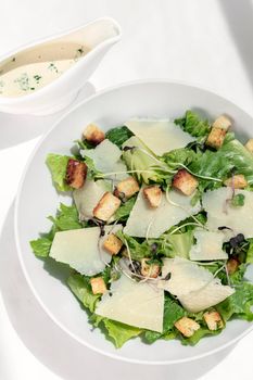 caesar salad with parmesan cheese and croutons on white table