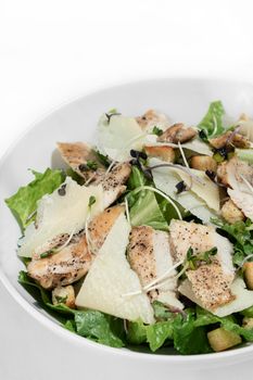 organic chicken caesar salad with parmesan cheese and croutons on white table background