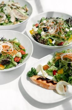 mixed fresh organic salads in bowls on white restaurant table