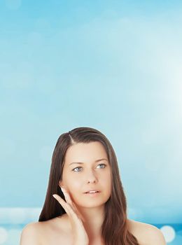 Skincare and sun protection in summer. Portrait of a beautiful young suntanned woman, blue sea and sky on background, beauty, wellness and travel concept.