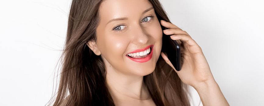 Happy suntanned woman smiling and calling on smartphone on holiday, portrait on white background. People, technology and communication concept.