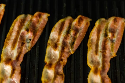 thin slices of delicious bacon fried on the grill, crispy and delicate meat, appetizer