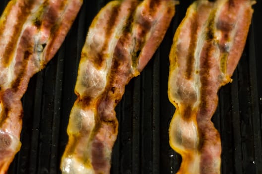 thin slices of delicious bacon fried on the grill, crispy and delicate meat, appetizer