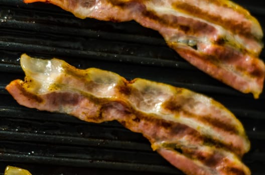 thin slices of delicious bacon fried on the grill, crispy and delicate meat, appetizer