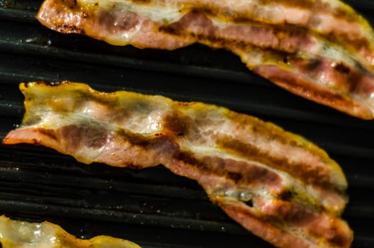 thin slices of delicious bacon fried on the grill, crispy and delicate meat, appetizer