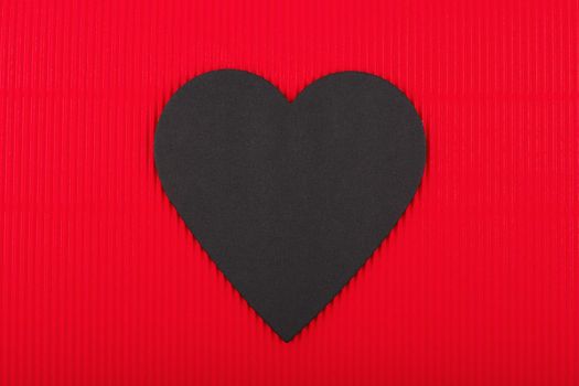 Top view of black paper heart on red background. Concept of love, Valentine's day and relationship