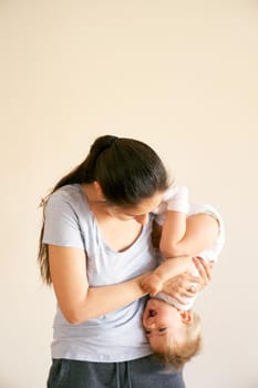 Mom holds a little laughing girl upside down in her arms. High quality photo