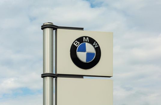 GERMANY, STUTTGART - May 15, 2021: BMW logo on a white banner against a blue cloudy sky. Stock photo.