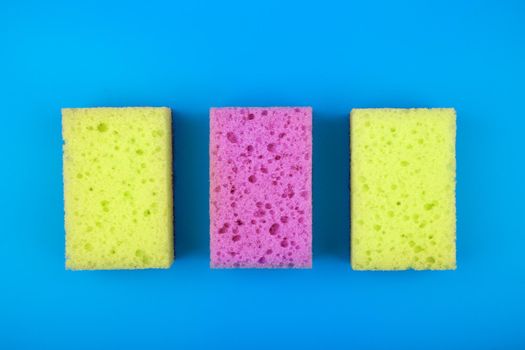 Colorful flat lay with with yellow andpurple sponges for house cleaning and dish washing on blue background. Concept of cleaning tools for home