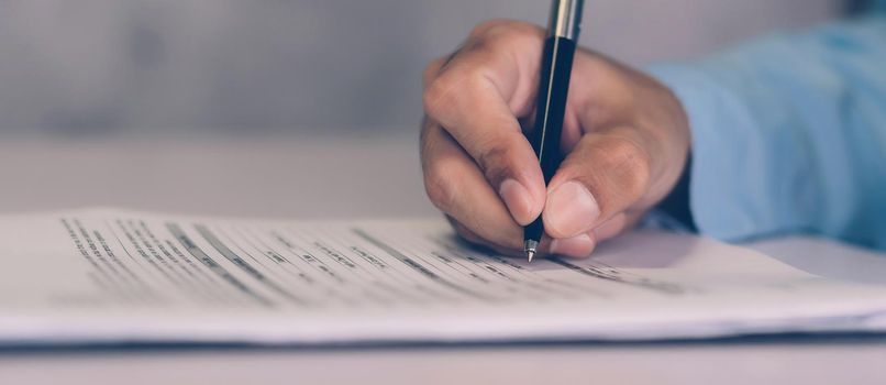 Hands of businessman signing contract about agreement for success on desk in the office, man signature document paperwork with pen, legal insurance and decision for deal, business concept.