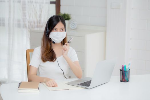 Young asian woman wearing headphone study online with e-learning on desk, girl wearing headset learning to internet with laptop computer at home, new normal, distance education and training.