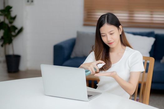 Young asian woman work from home with alcohol gel or sanitizer for cleaning hand and protect coronavirus or covid-19, new normal, quarantine and social distancing, businesswoman using laptop computer.