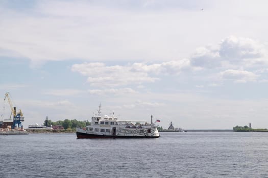 Kronshtadt, St. Petersburg, Russia - June 06, 2021 A pleasure boat with tourists arrives at the pier in the harbor. Selective focus.