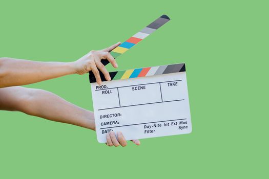 Hand holding film slate colors board for movie cinema and television industry on green background