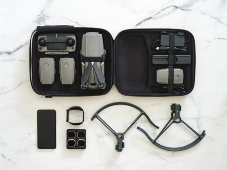 Drone quadcopter with full set. Top view or flat lay kit of drone UAV in case and accessories over white marble background