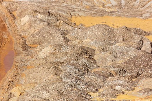 Photograph of crushed sand and stone laying on the ground in a large quarry