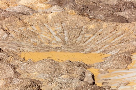 Photograph of crushed sand and stone laying on the ground in a large quarry