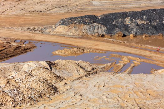 Photograph of stagnant flood water lying on the ground in a large quarry