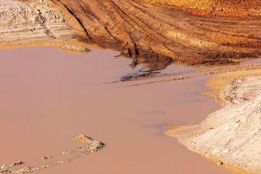 Photograph of stagnant flood water lying on the ground in a large quarry