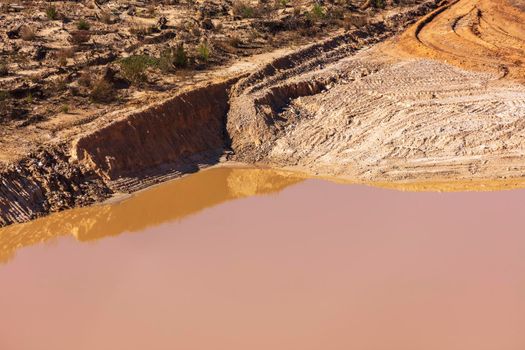 Photograph of stagnant flood water lying on the ground in a large quarry