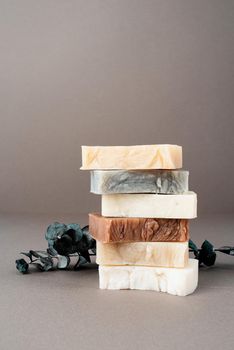 Stack of various handmade soap and eucalyptus on gray background, front view