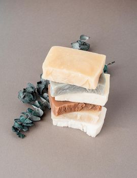 Stack of various handmade soap and eucalyptus on gray background, front view