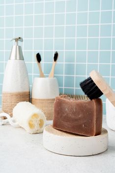 Bath accessories with bamboo brushes, handmade soap, dispenser and natural brushes on bath shelf, front view