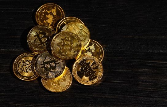 Leader in cryptocurrency bitcoin BTC on a top of coins against black wooden surface. Closeup golden coin with bitcoin logo. Stack of decentralized digital currency. Crypto payment. Electronic money