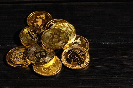 Leader in cryptocurrency bitcoin BTC on a top of coins against black wooden surface. Closeup golden coin with bitcoin logo. Stack of decentralized digital currency. Crypto payment. Electronic money
