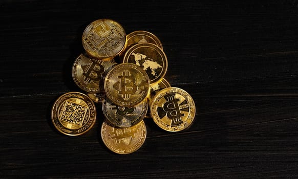 Leader in cryptocurrency bitcoin BTC on a top of coins against black wooden surface. Closeup golden coin with bitcoin logo. Stack of decentralized digital currency. Crypto payment. Electronic money