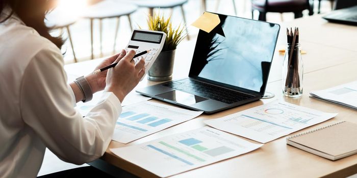 businesswoman working on desk office with using a calculator to calculate the numbers, finance accounting concept