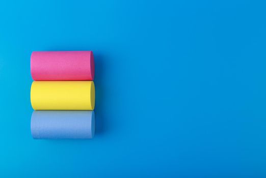 Flat lay with pansexual flag made of pink, yellow and blue rolls on blue background with copy space. Concept of pansexual community, sexual minorities, equal right and tolerance