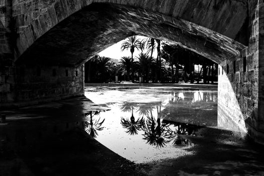 Stone bridge and reflections in a park puddle