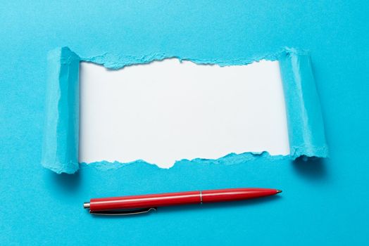 Tear on sheet reveals background with pen on board