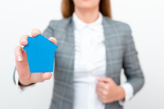 A Young Lady Businesswoman Holding Presenting Home In Business Outfit