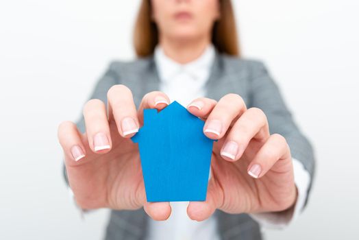A Young Lady Businesswoman Holding Presenting Home In Business Outfit