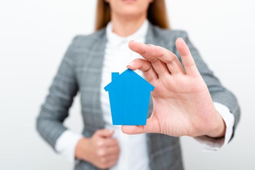 A Young Lady Businesswoman Holding Presenting Home In Business Outfit