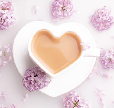 Cappuccino coffee in a cup and a branch of lilac on a white background . A hot drink. relax. The concept of cafeteria advertising. Article about cappuccino. Making cappuccino. Lilac branches. Spring.