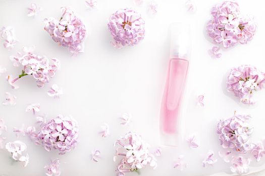 Pink perfume bottle and lilac branch on a white background. The concept of advertising perfumes. A bottle of perfume without text. Floral aromatherapy layout . Copy space