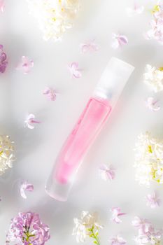 Pink perfume bottle and lilac branch on a white background. The concept of advertising perfumes. A bottle of perfume without text. Floral aromatherapy layout . Copy space