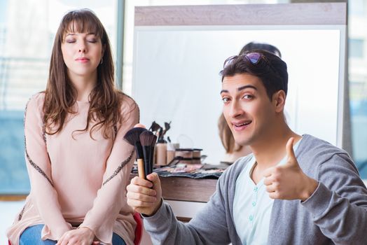 Man doing make-up for cute woman in beauty salon