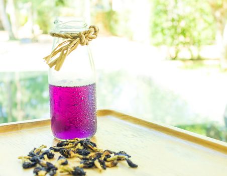 Butterfly pea juice is placed in a wooden tray with dried butterfly pea flowers. Thai herbs for health 