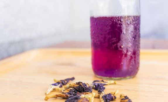 Butterfly pea juice is placed in a wooden tray with dried butterfly pea flowers. Thai herbs for health 